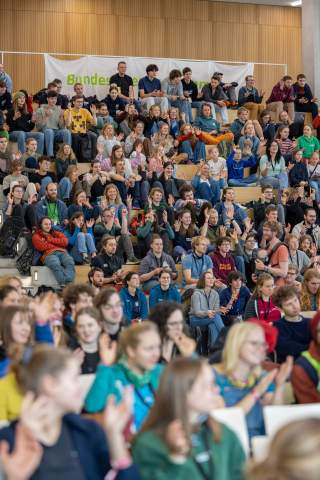 Viele junge Menschen sitzen auf einer Tribüne und klatschen