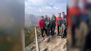 Gruppe von Menschen auf Aussichtsplattform über herbstlichem Wald
