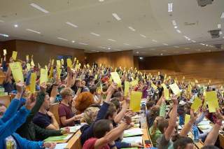 Abstimmung im Plenum, viele junge Menschen halten Stimmzettel hoch