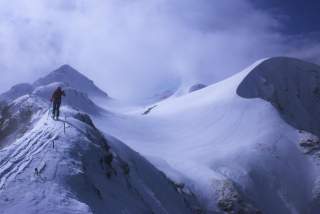 Ein einsamer Skibergsteiger läuft über ein Schneefeld