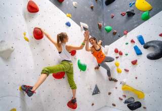 Zwei Boulderinnen geben sich während sie klettern einen High Five