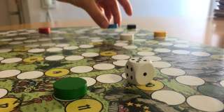 Ein Brettspiel mit 6 bunten Spielsteinen und einem Würfel