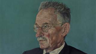 Porträt eines älteren Mannes mit grauem Haar, Brille und Schnurrbart vor grünem Hintergrund.