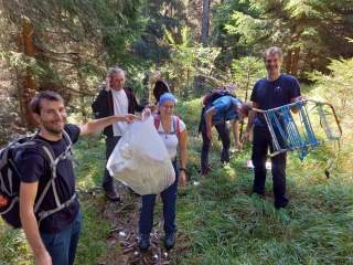 Gruppe Jugendlicher sammelt Müll in der Natur. Die Plastiktüte ist voll.