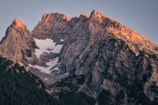 Berggipfel in den Alpen, teilweise mit Schnee bedeckt, im warmen Licht der untergehenden Sonne.